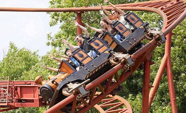 People on rollercoaster train descending at speed.