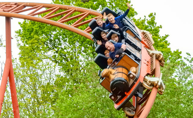 People onboard a rollercoaster train descending at speed.