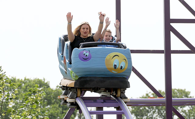 Woman and young boy in blue rollercoaster carriage on a purple track