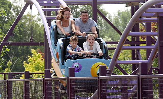 Family on rollercoaster with blue carriage and purple track