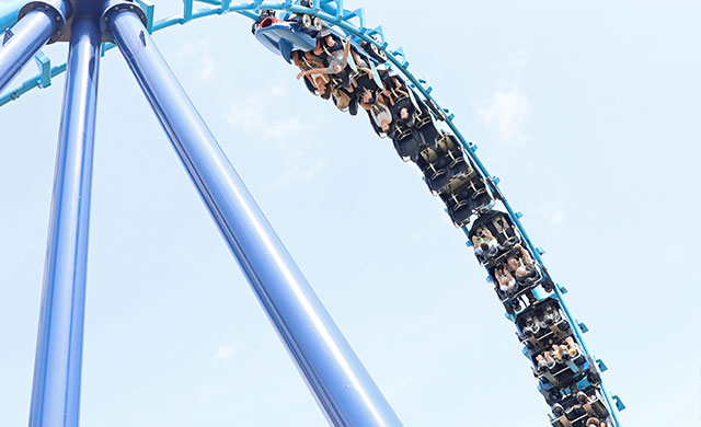 blue rollercoaster in a cobra roll with blue sky