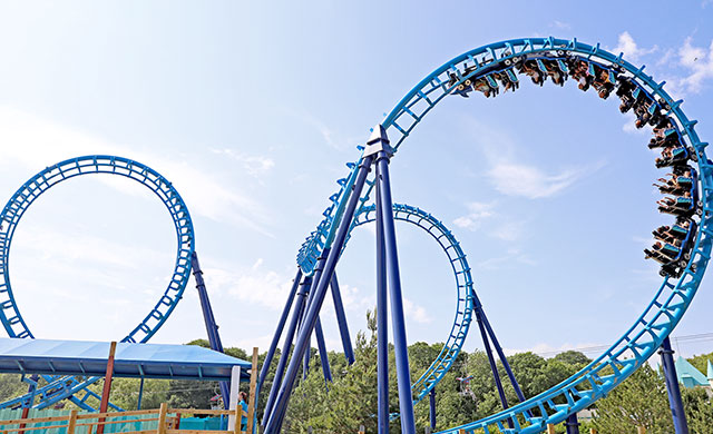 blue rollercoaster with blue sky and trees