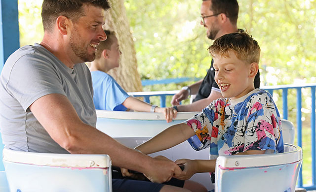 Man and young boy on teacups amusement ride